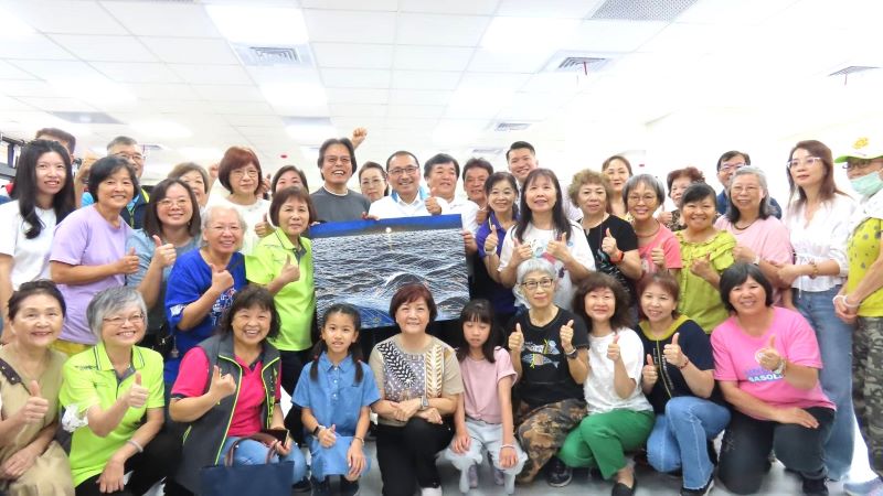 《圖說》侯友宜市長前往活動中心內的繪畫課程，與學員們互動熱絡合影，留下日出畫作。〈民政局提供〉